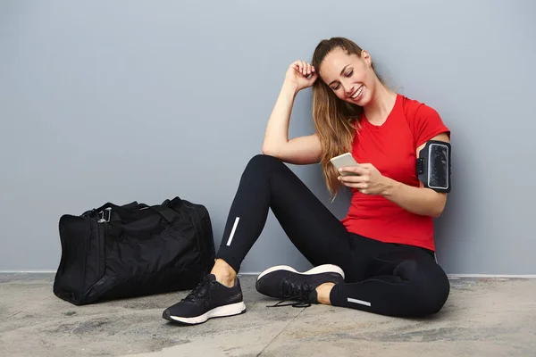 Lächelnde athletische Frau mit Handy — Stockfoto