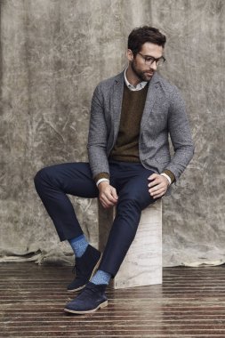 Kutu üzerinde oturan gözlüklü adam