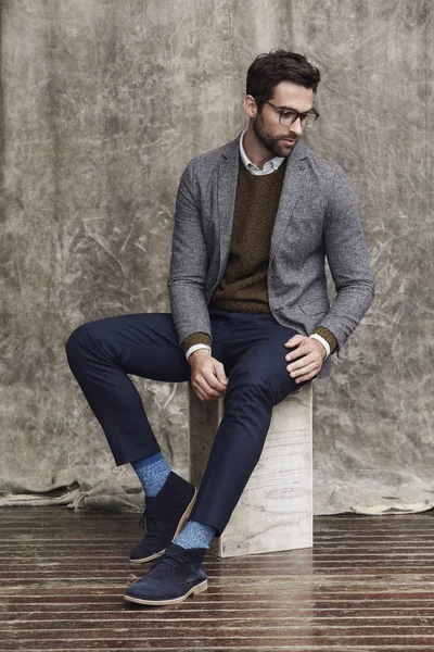 Kutu üzerinde oturan gözlüklü adam