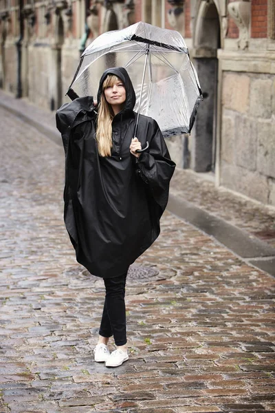 Junge Frau im schwarzen Regenmantel — Stockfoto