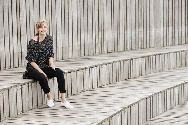 Kobieta siedzi na drewnianych schodkach — Zdjęcie stockowe