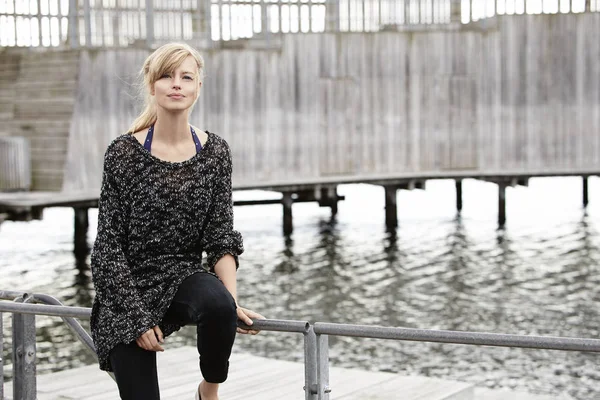 Junge Frau sitzt auf Seebrücke — Stockfoto