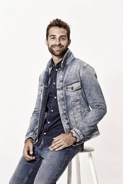 Taburede denim giysiler giyiyor adam