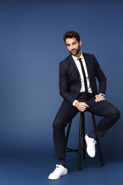 Taburede oturan takım elbiseli adam