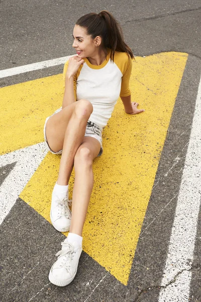 Menina bonita sentada na estrada — Fotografia de Stock