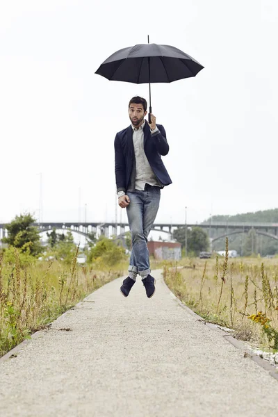 Mann springt mit Regenschirm — Stockfoto