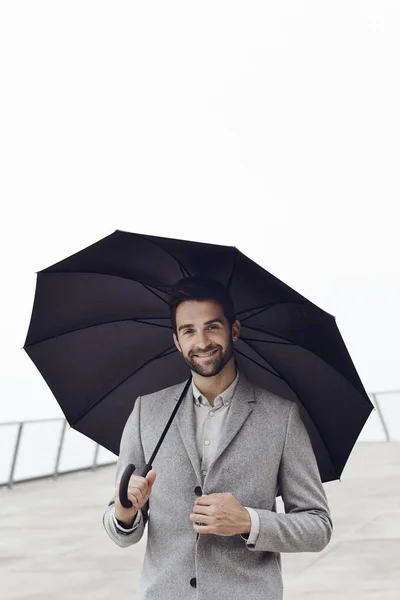 Mann lächelt mit Regenschirm — Stockfoto