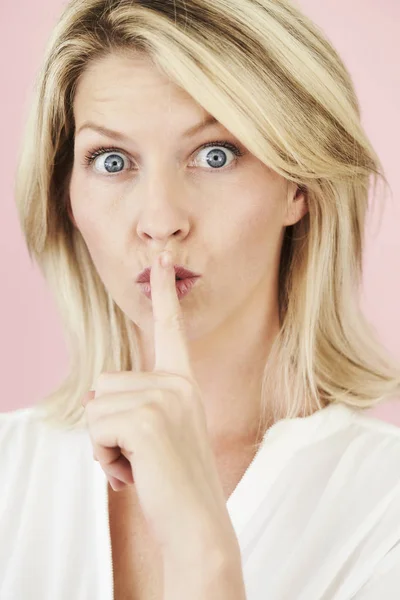 Blonde vrouw met geheime gebaar — Stockfoto