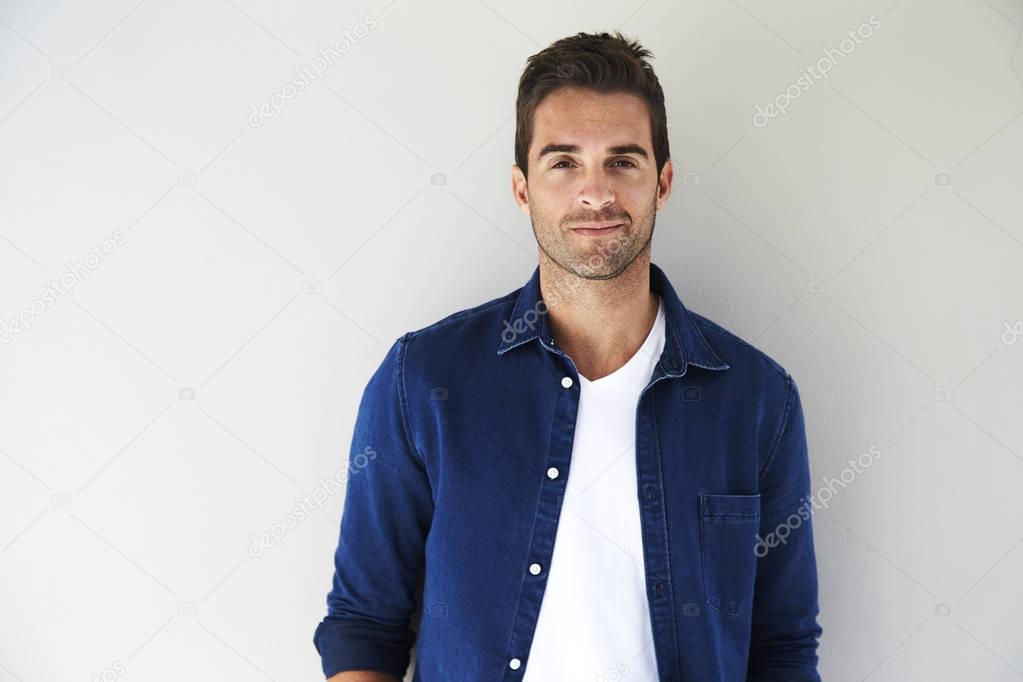 Handsome young man standing by white wall