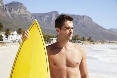 plajda surfboard ile yakışıklı sörfçü