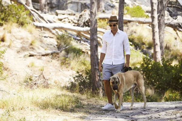 Giovane con gli occhiali da sole che cammina con il cane — Foto Stock