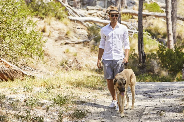 Ung man i solglasögon promenader med hunden — Stockfoto