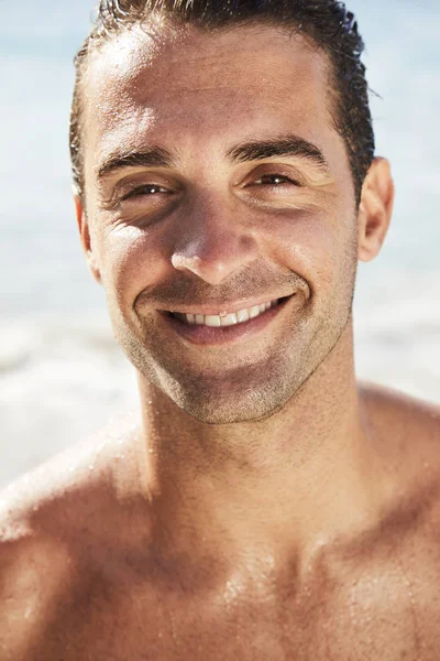 Uomo sorridente in spiaggia guardando la fotocamera — Foto Stock