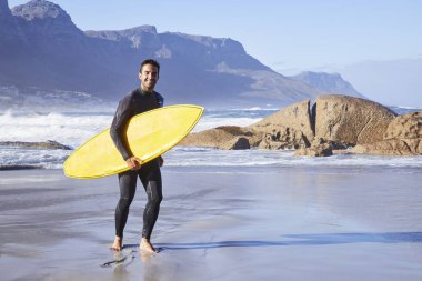 Sahilde kurulu taşıyan sörfçü 