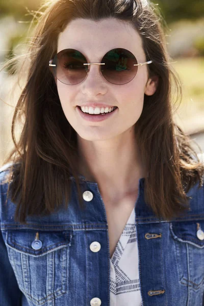 Mladá bruneta žena s úsměvem v sluneční brýle — Stock fotografie