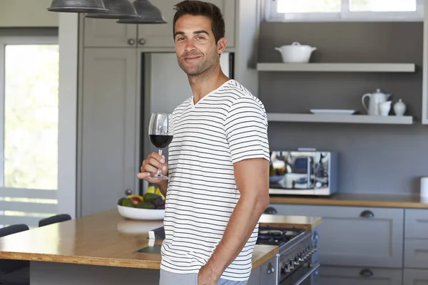 Homem com copo de vinho na cozinha — Fotografia de Stock