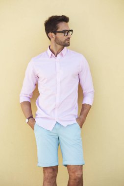 duvar dibinde duran gözlüklü adam