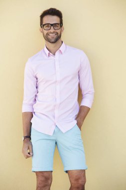 duvar dibinde duran gözlüklü adam