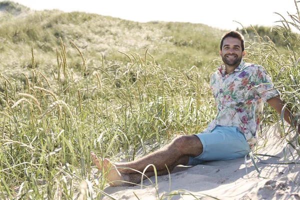 Glücklicher Mann auf Gras sitzend — Stockfoto