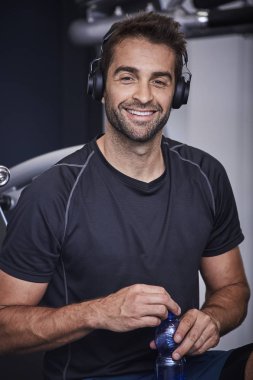 Kulaklıklar ile spor salonunda gülümseyen adam