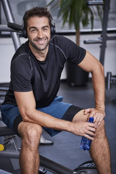 Glimlachende man in sportschool met koptelefoon — Stockfoto