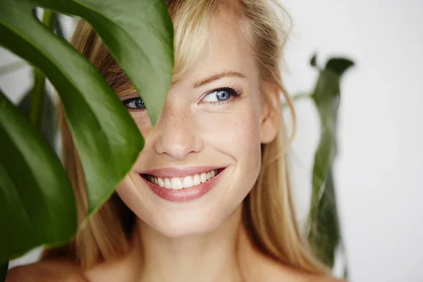 Портрет улыбающейся женщины за листом — стоковое фото