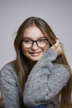 Genç kadın gözlük ve gri kazak, gülümseyen