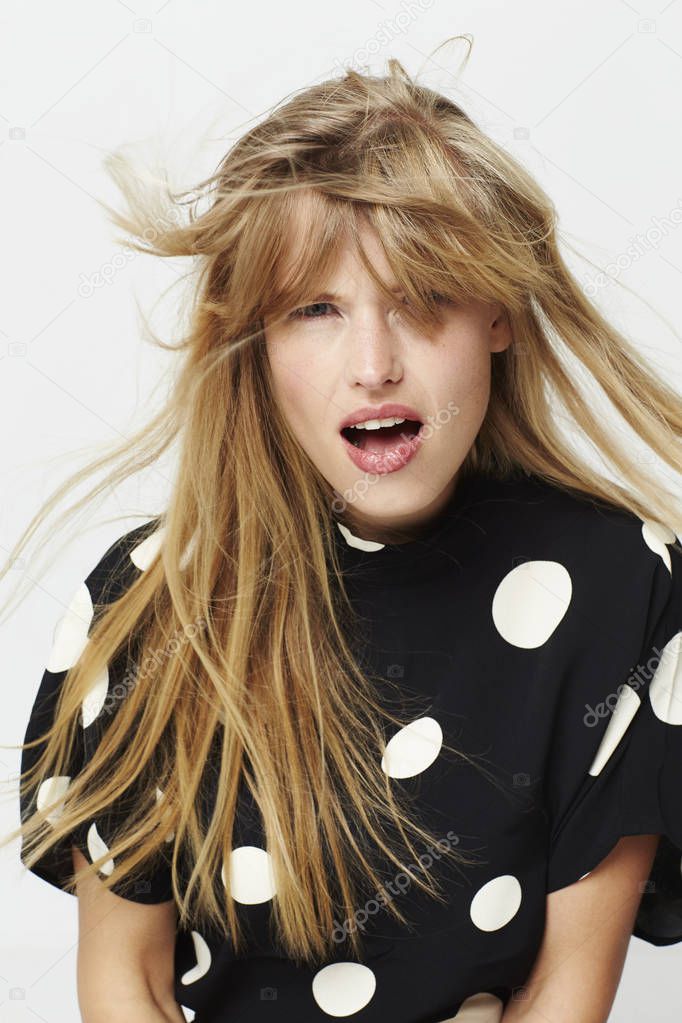 Blond and windswept young woman in studio, portrait