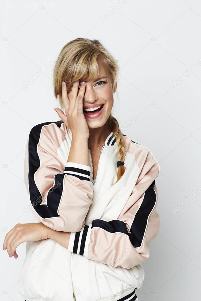 Laughing girl looking to camera, hand over her eye