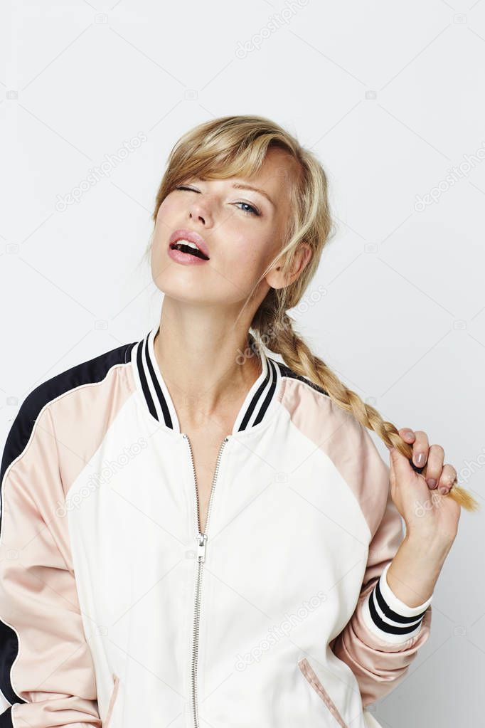 Portrait of winking girl holding braid, looking at camera