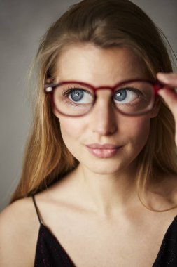Bir kenara seyir gözlük tutan büyük mavi gözlü kadın portresi