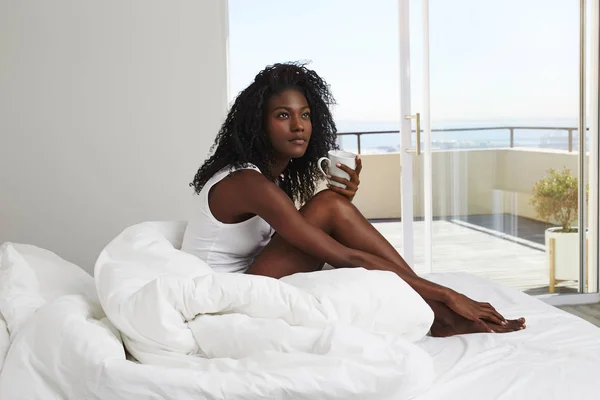 よそ見ベッド コーヒー カップを持つ若いアフリカ系女性 — ストック写真