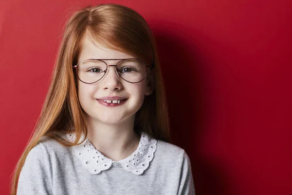 Portrét Červenovlasá Dívka Brýlích Usmívá Kameru Červeném Pozadí — Stock fotografie