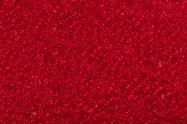 Seed beads of dark red color on the textile background.