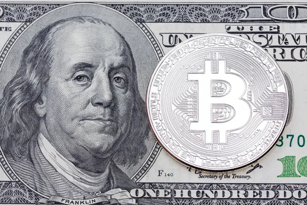 Yüz dolarlık banknot üzerinde gümüş bitcoin.