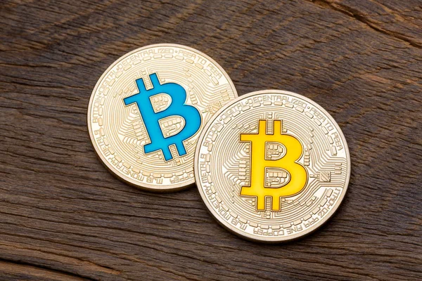 Primer plano de bitcoins azules y amarillos dorados sobre fondo de madera , — Foto de Stock