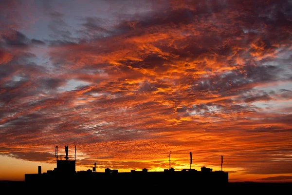 Beautiful background with sky with clouds and silhouette of the roof of the house with antennas.