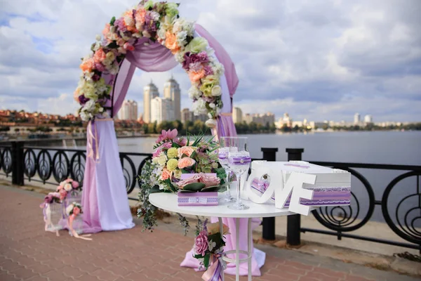 Роскошная свадебная арка на берегу реки с фиолетовыми и розовыми лентами — стоковое фото