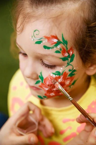 Çocuğun yüzünde bir çocuğun makyaj çizim sürecini