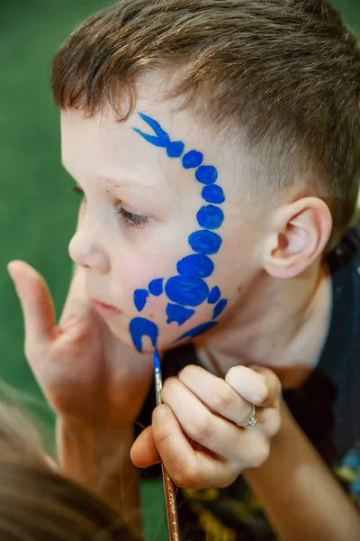 Çocuğun yüzünde bir çocuğun makyaj çizim sürecini