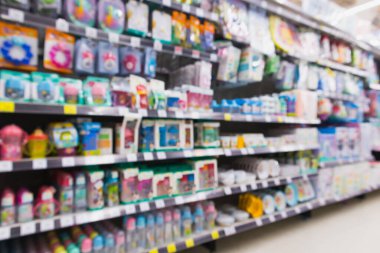 Bebek sütü şişelerinin ve bebek aksesuarlarının bulanık çeşitleri süpermarketteki raflarda. Bulanık efekt arka planı.