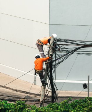 Elektrikçiler elektrik hatlarını kurmak ve onarmak için elektrik direklerine tırmanıyorlar..