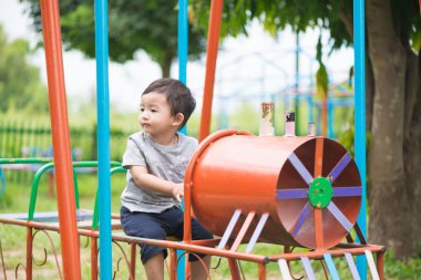 Genç Asyalı çocuk oyun bahçesi und sallanan bir demir tren