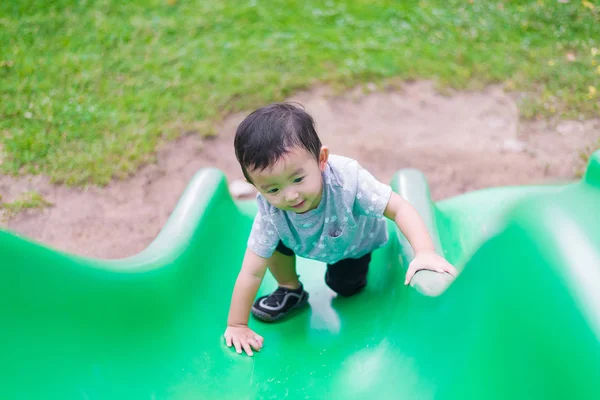 Piccolo bambino asiatico che sale sullo scivolo al parco giochi in summ — Foto Stock