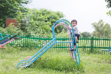 Küçük Asyalı çocuk slayt parkta oynarken