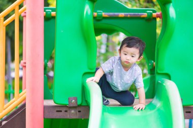 Küçük Asyalı çocuk slayt parkta oynarken