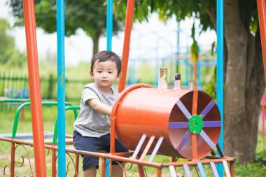 Genç Asyalı çocuk oyun bahçesi und sallanan bir demir tren