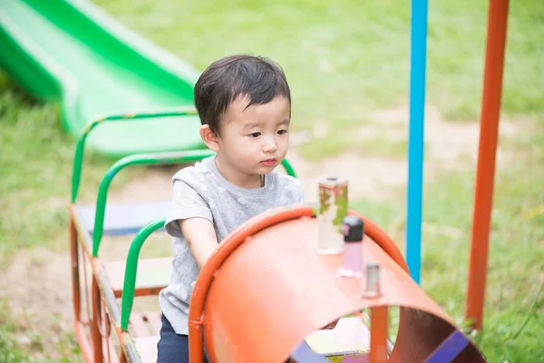 Aziatische jongen spelen een ijzeren trein swingen op de speelplaats-und — Stockfoto