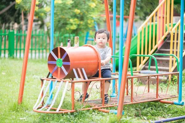 Jovem ásia menino jogar um ferro trem balançando no o playground und — Fotografia de Stock