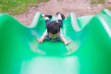 Küçük Asyalı çocuk oyun alanında summ, slayt yukarı tırmanma